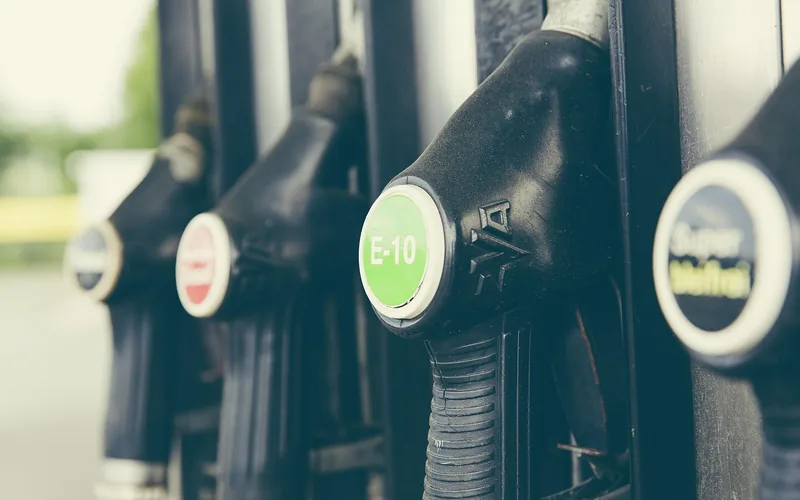 Row of gas station pump handles with fuel type labels