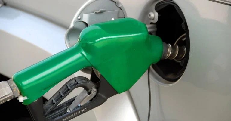 Green fuel nozzle inserted in a silver car fuel filler