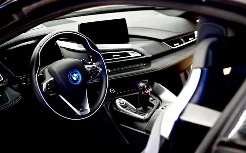 BMW dashboard and steering wheel showing the iDrive controller used to access auto start/stop settings