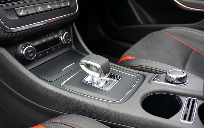 Car center console with an automatic gear selector and a rotary controller beside the cup holder