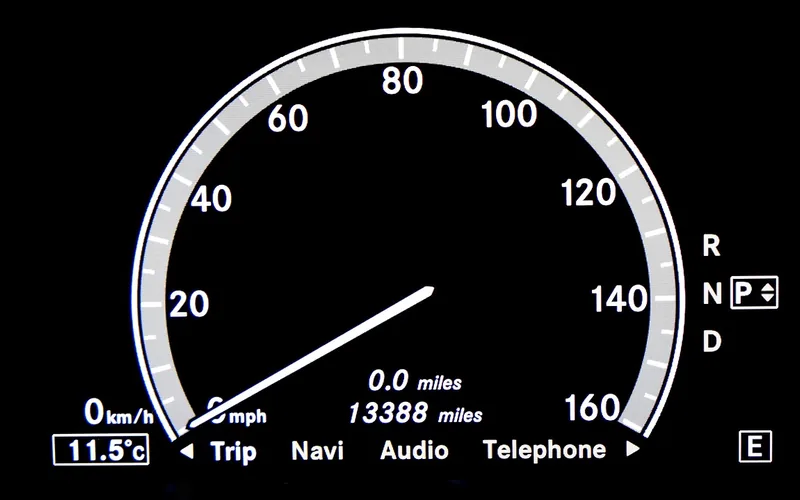 Car instrument cluster display with a speedometer and Trip, Navi, Audio and Telephone menu labels