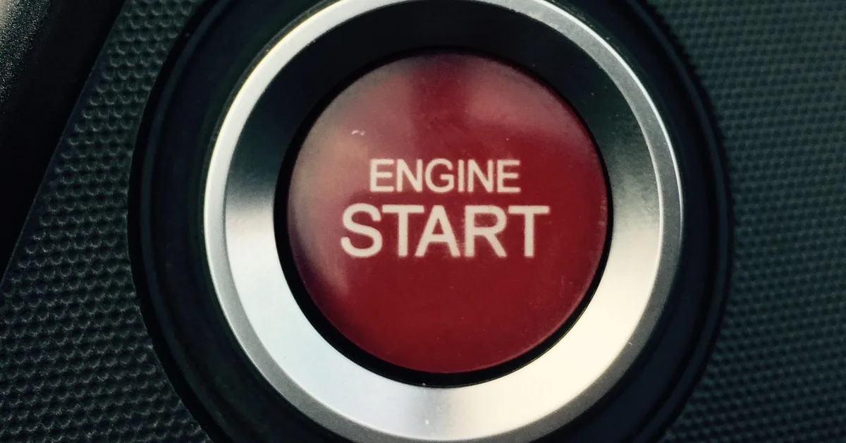 Red engine start button in a ring on a car dashboard panel