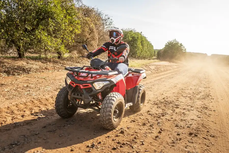 ATV rider wearing a helmet on a dusty dirt road