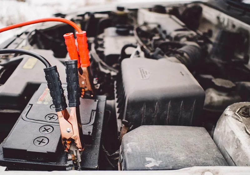 Cable clamps attached to a car battery under the hood