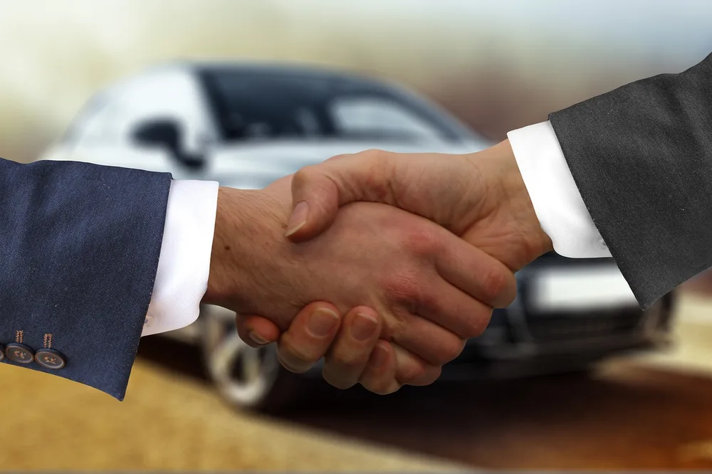 Customer and dealer shaking hands after agreeing on a car order