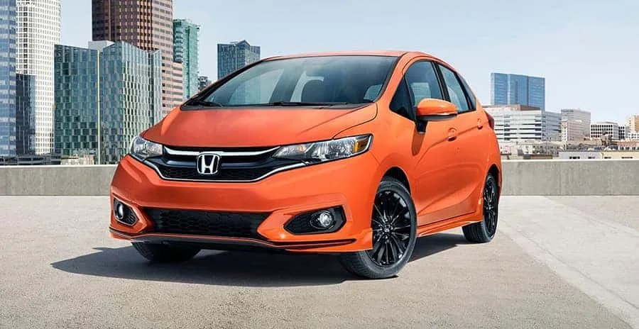 Orange Honda Fit Sport hatchback parked on a rooftop with city skyline