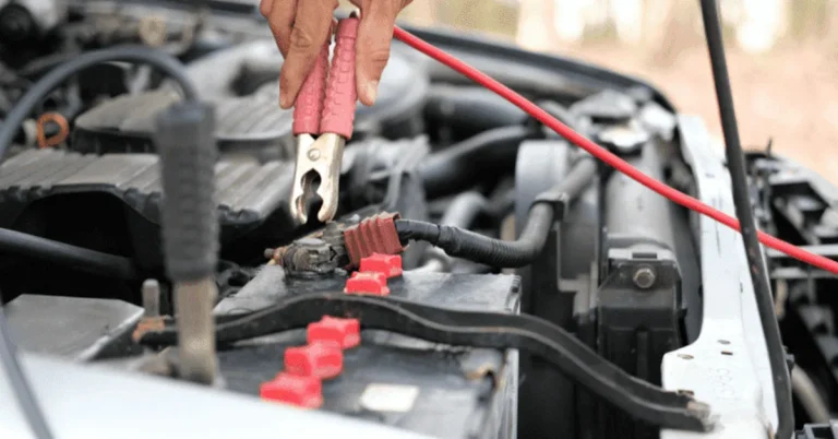 Jumper cables clamped onto a car battery to fix a discharged BMW battery