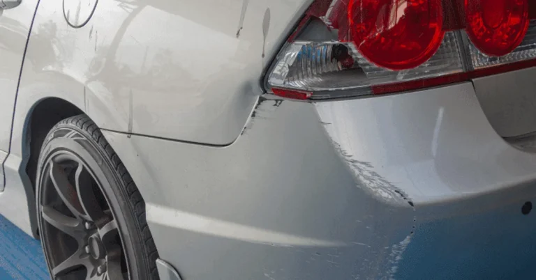 Scuffed and scratched paint on a car's rear quarter panel