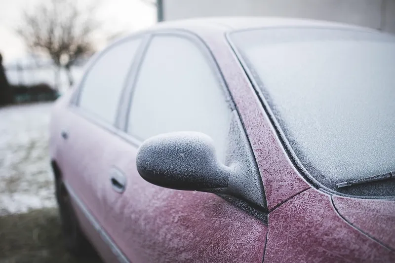 Frost-covered car and side mirror on a cold winter morning