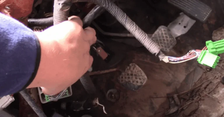 Mechanic unplugging a wiring connector near the relay and fuse box in an engine bay