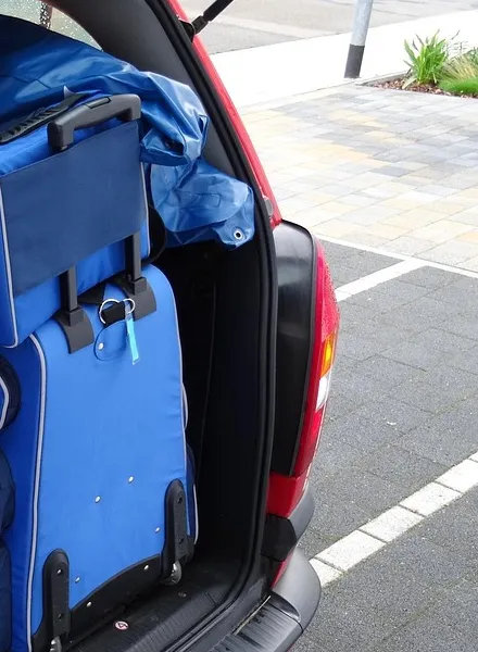 Blue luggage packed into the open rear cargo area of a hatchback
