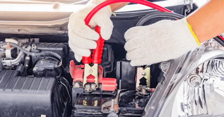Jumper cables connected to positive and negative terminals under a BMW hood