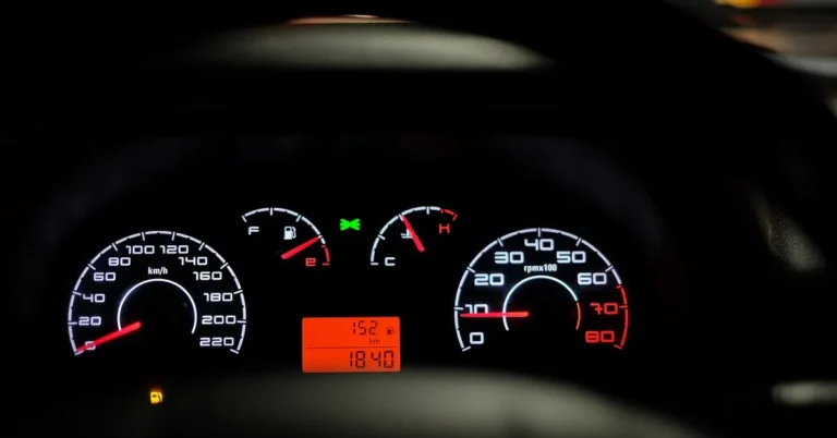 Car dashboard gauge cluster illuminated at night