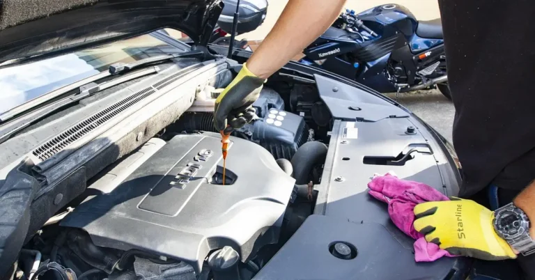Mechanic checking the oil dipstick under the hood to measure how many quarts a car needs