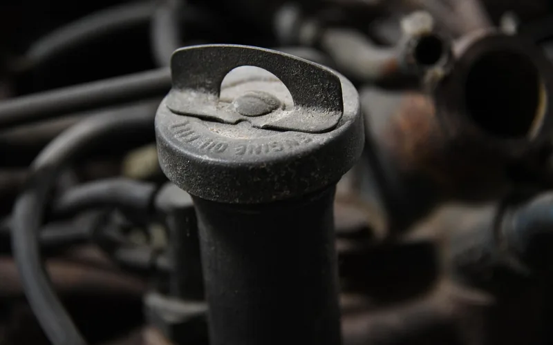 Engine oil fill cap being removed on a car engine, part of verifying fresh oil before resetting the maintenance minder