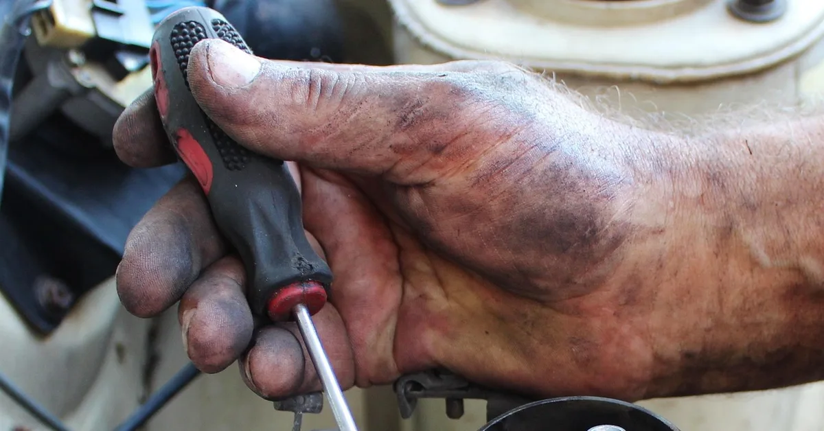Mechanic working on an engine to diagnose a Ford F150 coolant leak between the engine and transmission