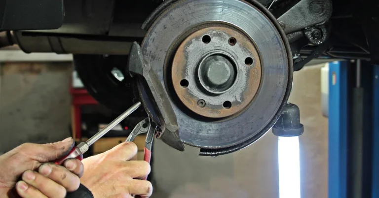 Mechanic inspecting a car brake disc and sensor area