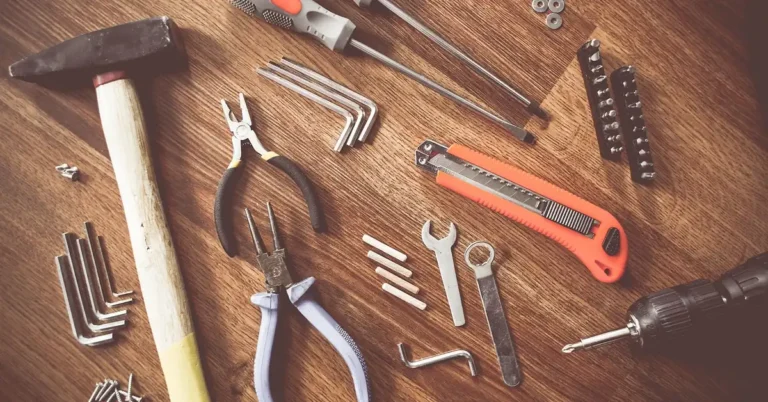 Screwdrivers, pliers, hex keys and screws laid out on a wooden table