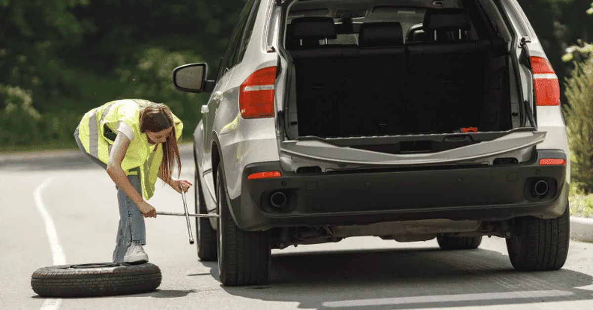 Person changing a tire at the rear of an SUV with the cargo area open