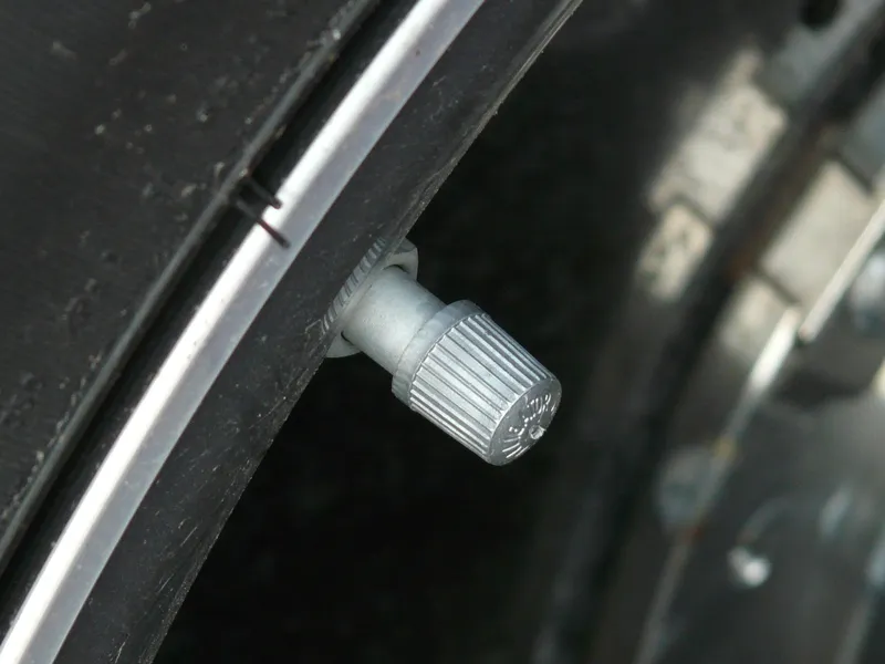 Close-up of a metal valve cap on a car wheel valve stem