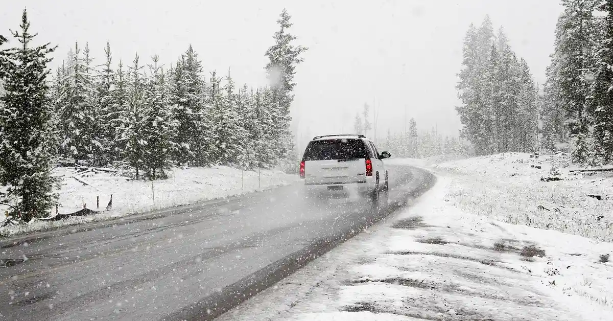 Sedan driving on a snow-covered road in winter conditions