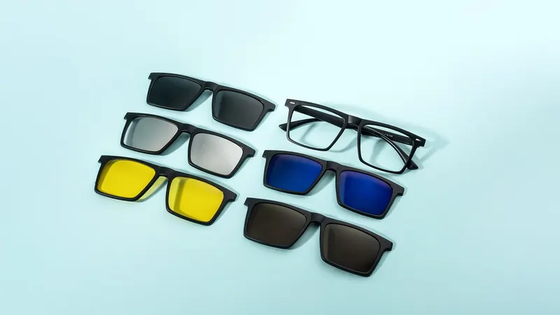 Set of clip-on sunglass lenses in several tints beside an eyeglass frame