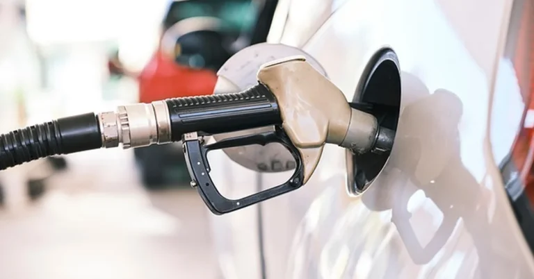 Fueling a white car at a gas station pump, relevant to E85 flex-fuel compatibility in the Ford Fusion