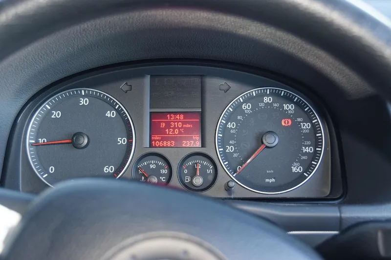 An instrument cluster with a red warning lamp lit next to the speedometer