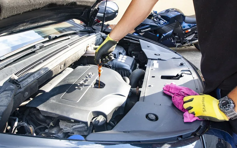 Mechanic checking motor oil viscosity during a Ford engine oil change