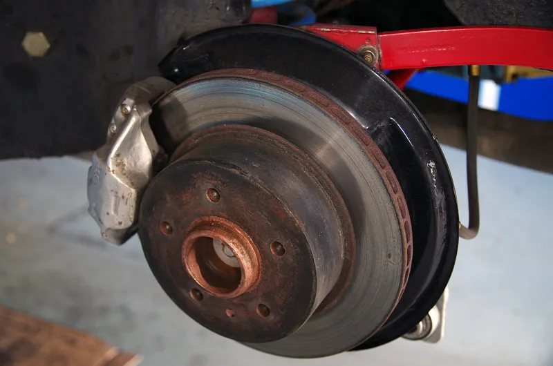 A rear brake disc and caliper on a car raised in a workshop