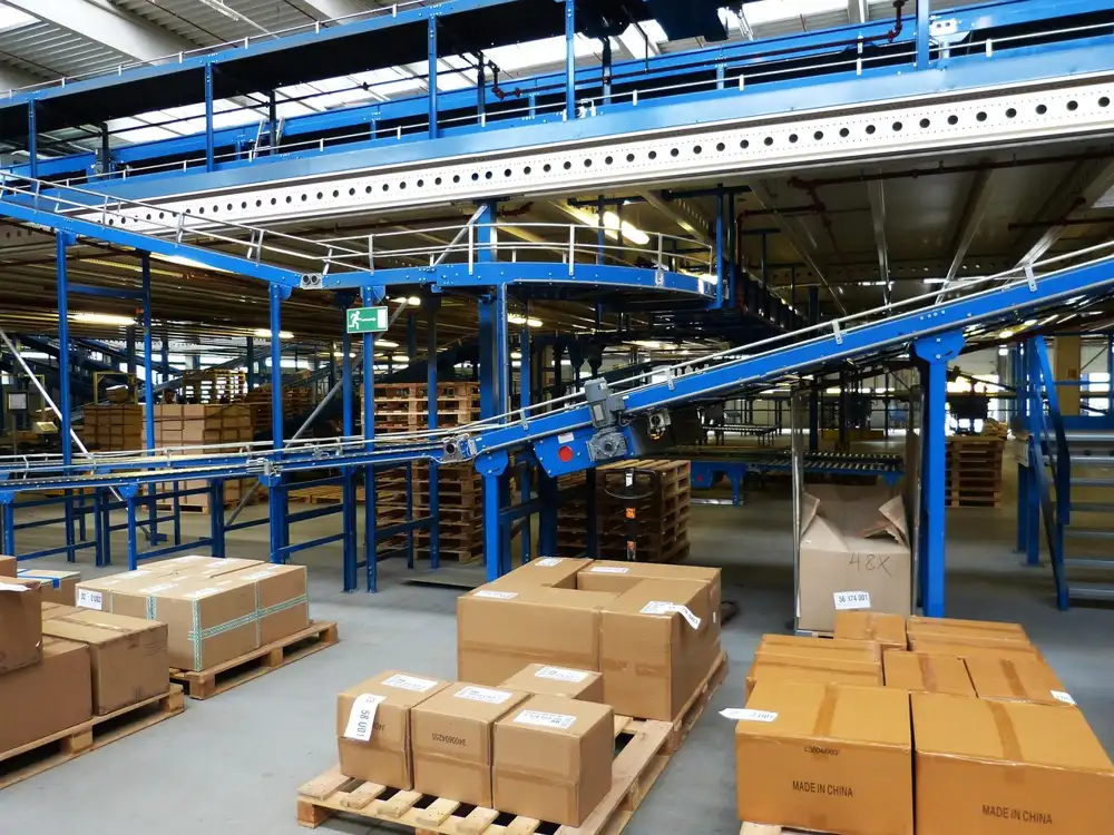 Cardboard boxes on pallets in a warehouse with overhead conveyors