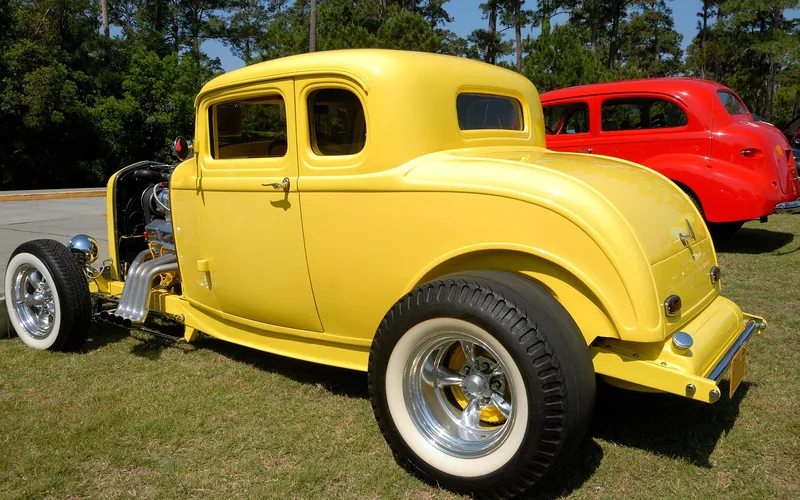 Yellow hot rod coupe with white wall tires parked on grass Yellow hot rod coupe with white wall tires parked on grass