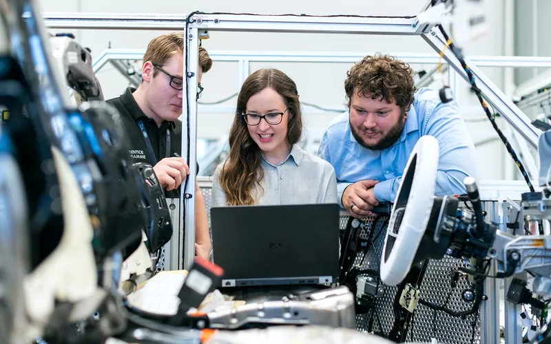 Automotive engineers reviewing vehicle diagnostics data on a laptop in a test lab Automotive engineers reviewing vehicle diagnostics data on a laptop in a test lab