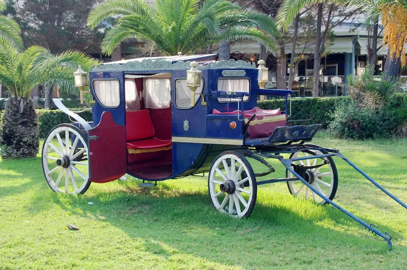 Blue and red horse-drawn carriage with white spoked wheels parked on a lawn