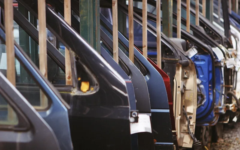 Car door and body panels lined up on racks in a car factory