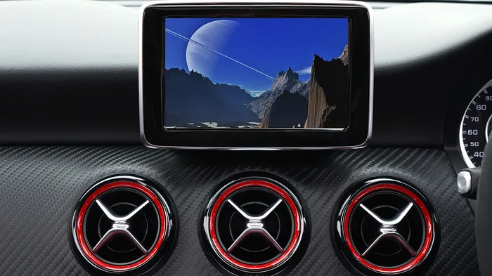 Car dashboard touchscreen display sitting above three round air vents