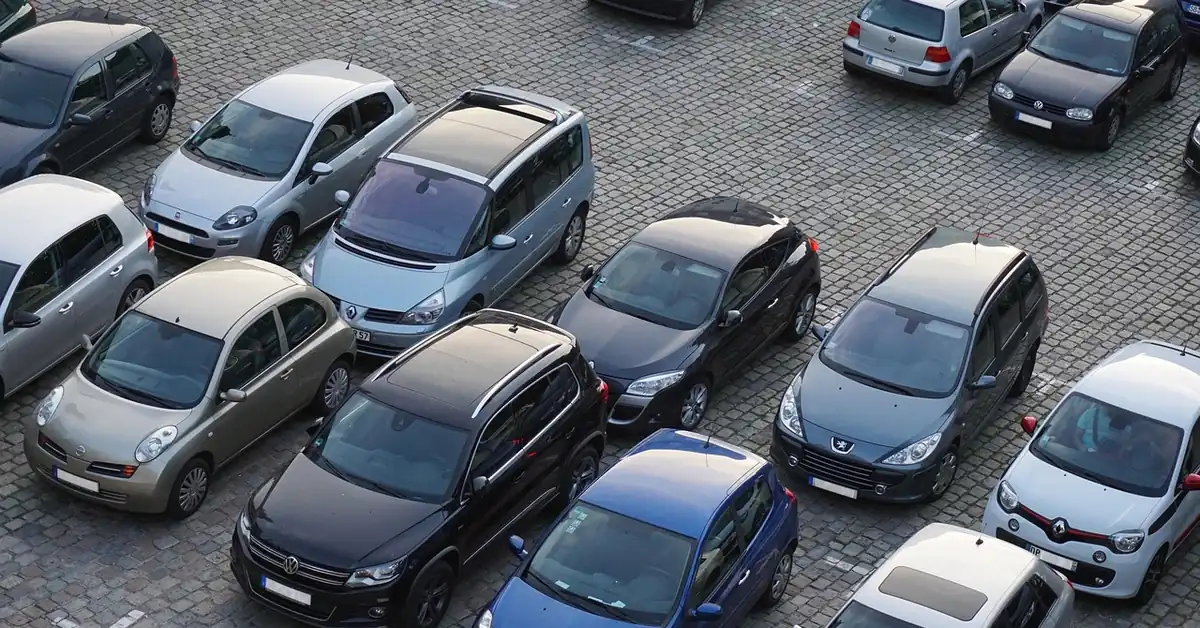 Overhead view of many different cars parked in rows on a cobblestone lot