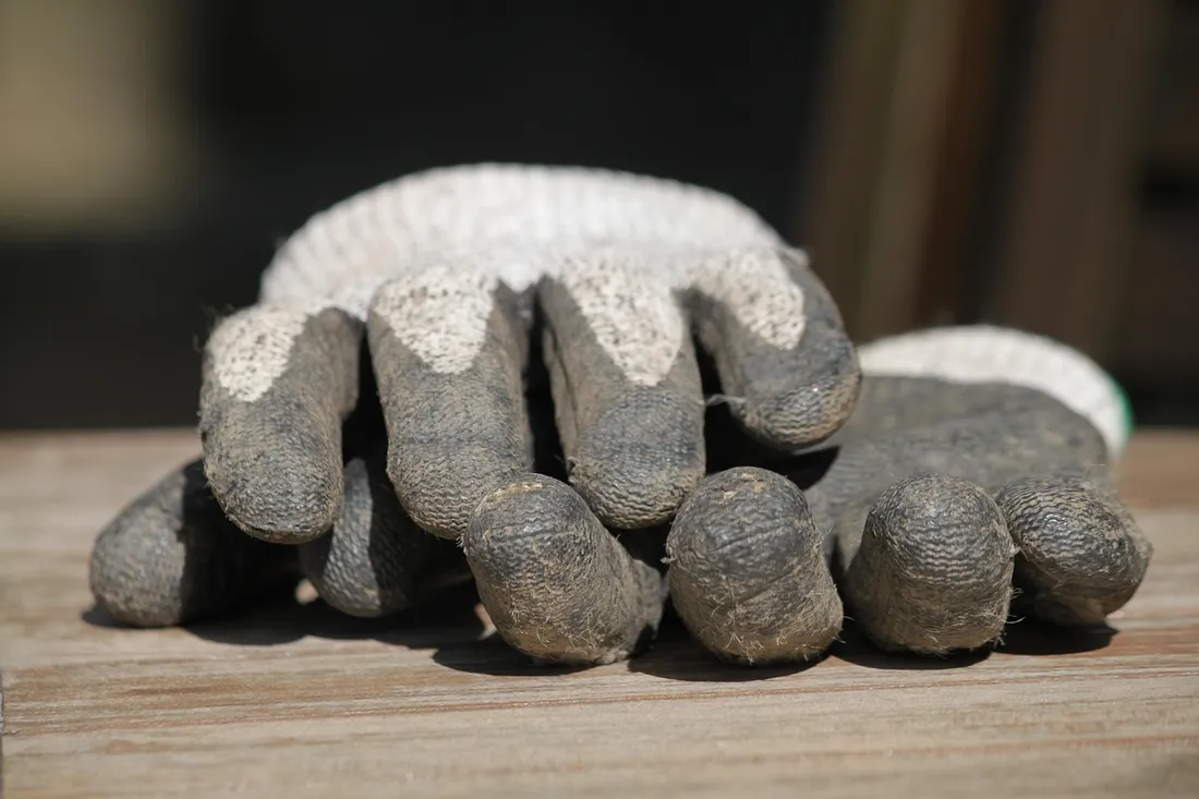 A pair of worn work gloves resting on a wooden surface