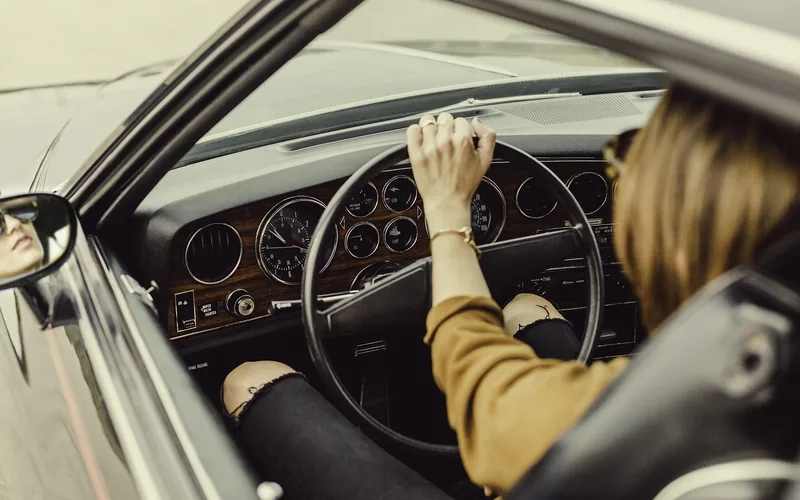 Driver's view of a car dashboard, speedometer, and steering wheel while driving Driver's view of a car dashboard, speedometer, and steering wheel while driving