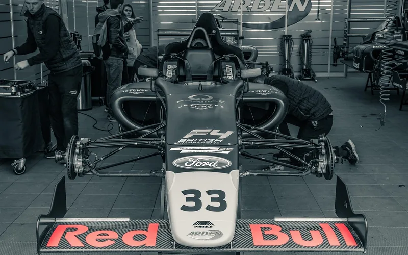 Race car in the pit lane garage with team crew working on the vehicle Race car in the pit lane garage with team crew working on the vehicle