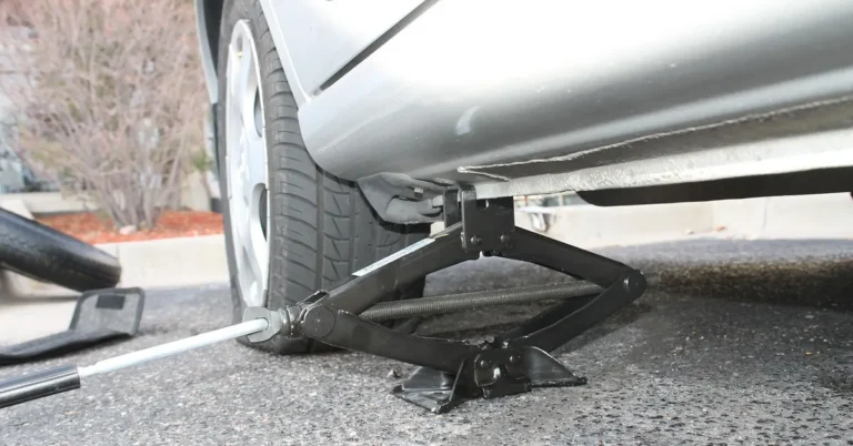 A flat tire being changed with a car jack