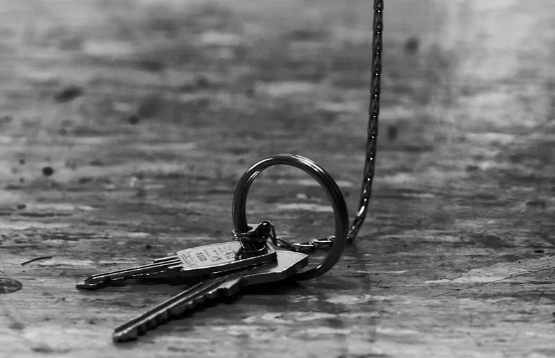 Set of keys on a ring lying on a worn wooden surface in black and white