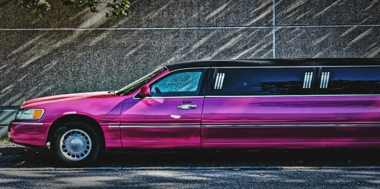 Pink stretch limousine parked beside a wall, side view