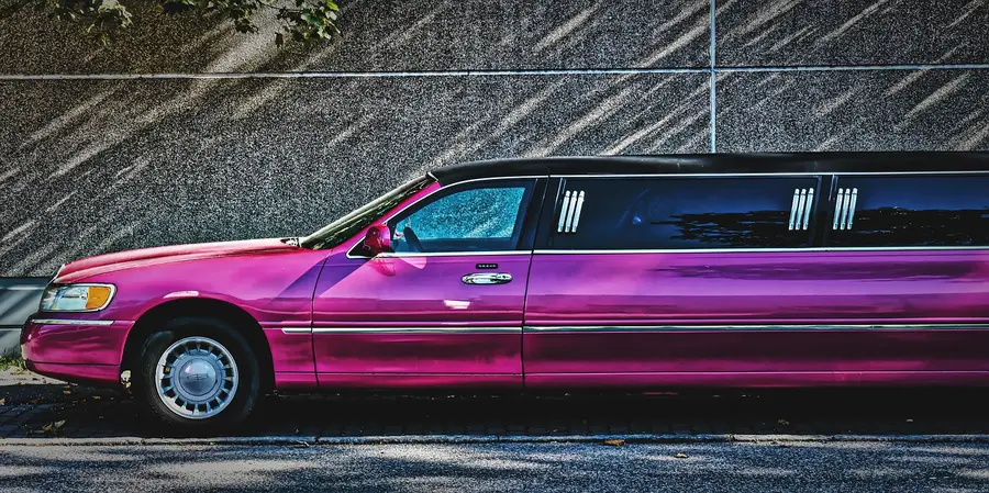 Pink stretch limousine parked beside a wall, side view