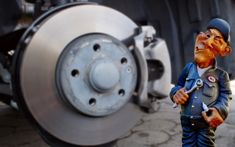 technician inspecting a brake disc and caliper during a vehicle safety service