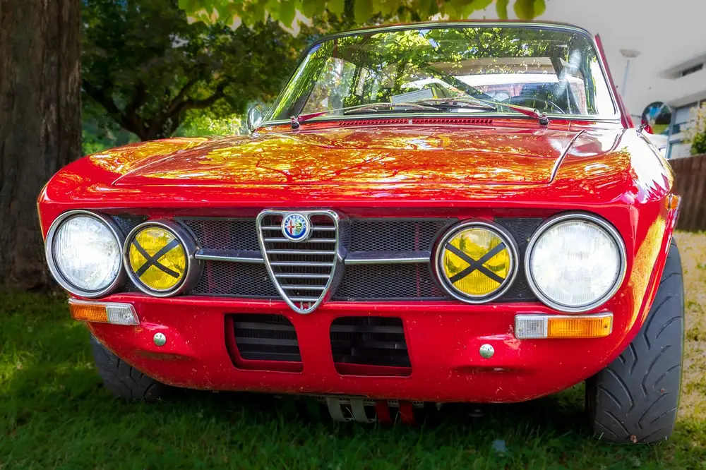 Front of a red vintage Alfa Romeo coupe with the shield grille