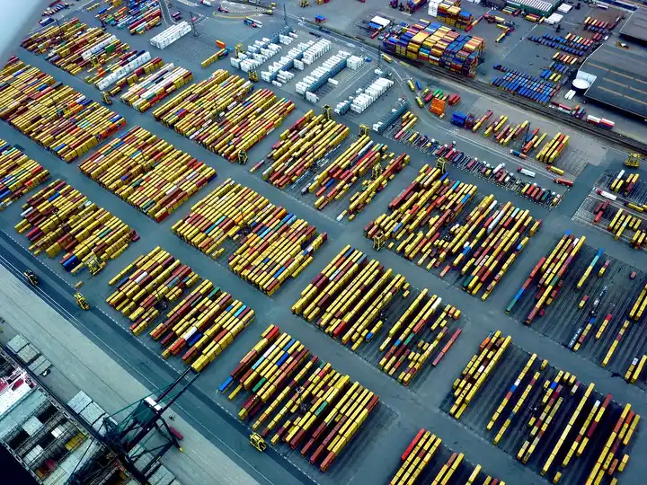 Aerial view of rows of stacked shipping containers in a large port container yard