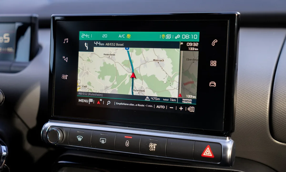 Car infotainment touchscreen on the dashboard showing a navigation map and route