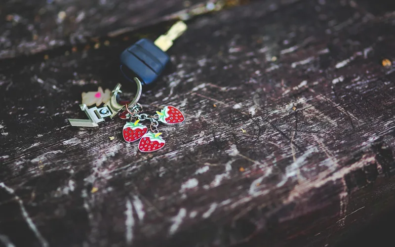Car key on a key ring with small charms resting on a wooden surface