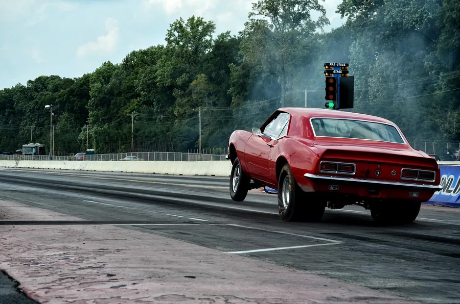 Car launching from the line at a drag strip with the staging light tree beside the lane